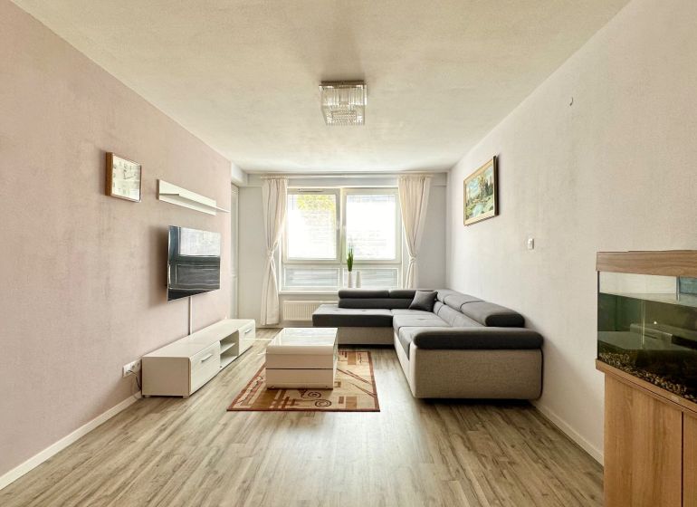Living room in a 3-room apartment with a corner sofa and a wooden decor floor.