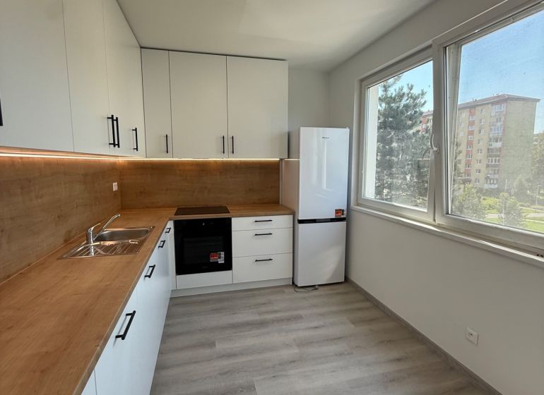 A kitchen in a 3-room apartment with white cabinets and a wood-patterned floor.