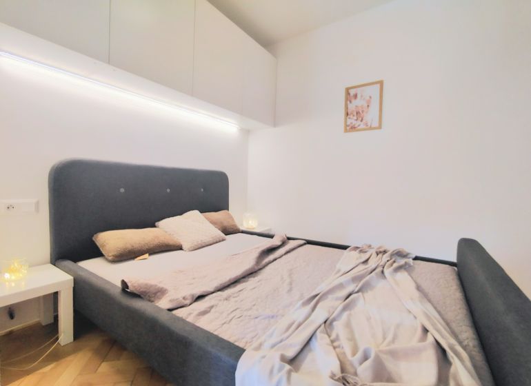 A bedroom with a comfortable bed, a white wardrobe, and decoration in a two-room apartment.