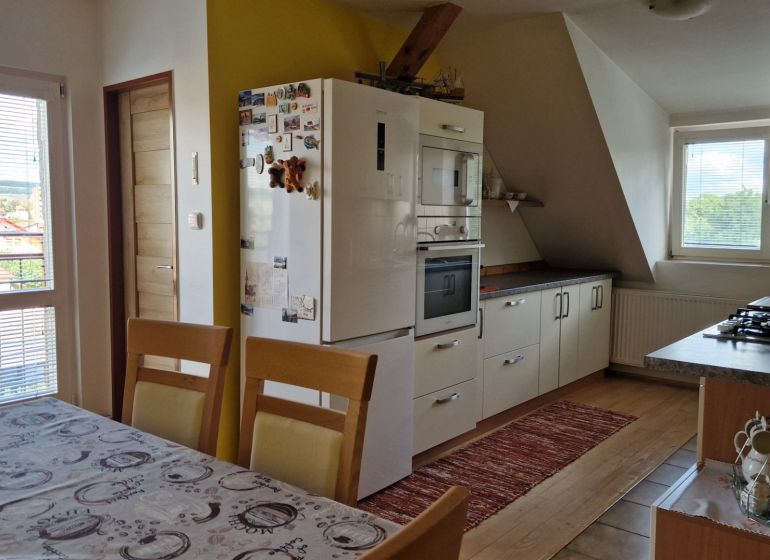 A kitchen in a 2-room apartment with a wooden decor floor and a dining table.