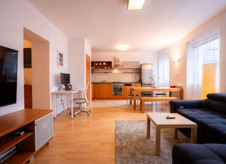 Living room with kitchen in a 4-room apartment, with a wooden decor floor and versatile furnishings.