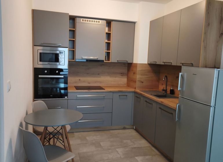 A kitchen in a studio apartment with a dining nook and gray cabinets.