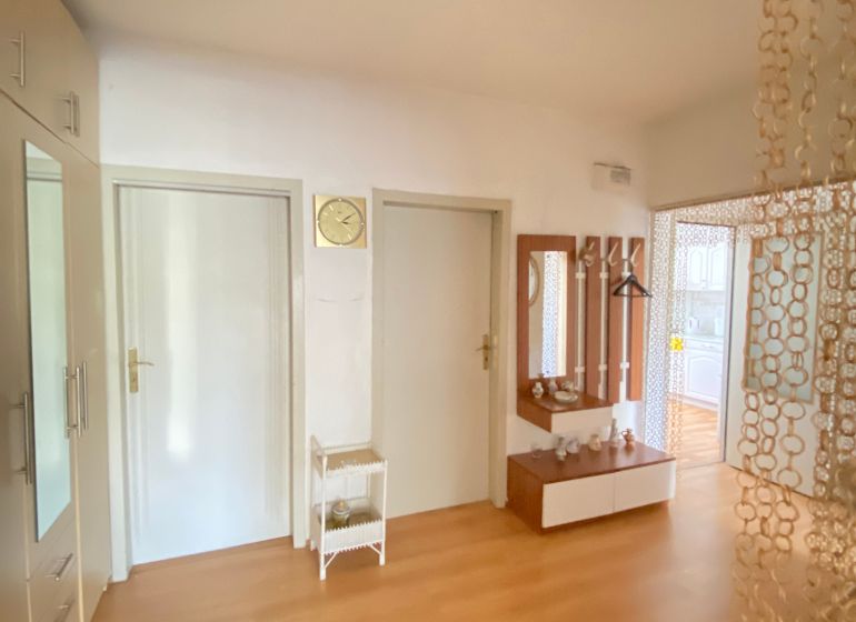 Entrance hall of a 4-room apartment with a wooden decor floor and a mirror.