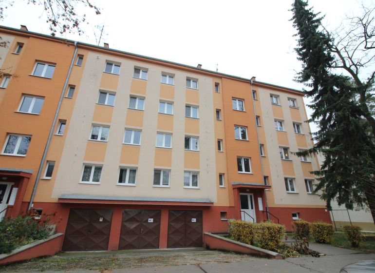 Apartment building in Trnava with a colorful facade, garages, and surroundings with trees.