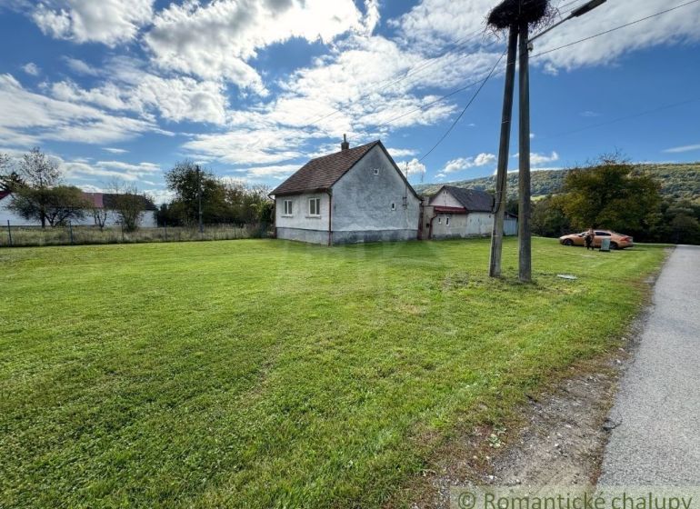 A family house in the village of Volica with a green lawn, an electric pole, and a parked car.