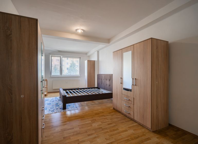 Bedroom in a 2-room apartment with a bed, wardrobes, and a floor with a wooden decor.
