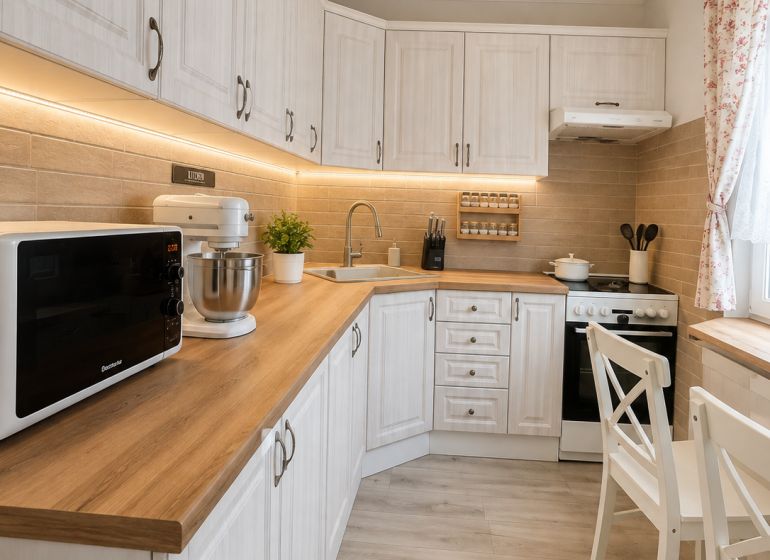 A kitchen in a three-room apartment with a wooden decor floor and white furniture.