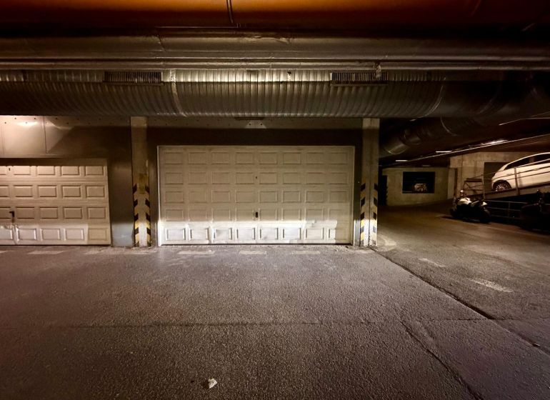 The interior of garages with closed doors and parked vehicles.