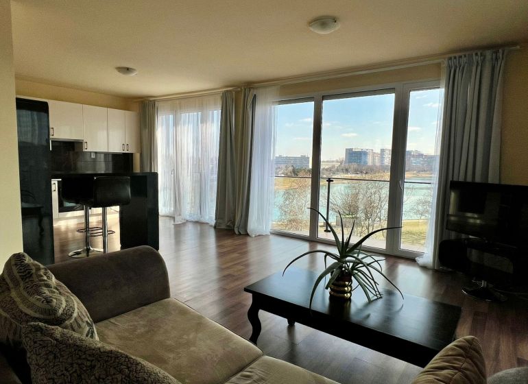 Living room in a 2-room apartment with large windows and a wooden decor floor.