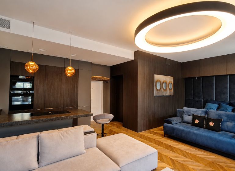 Living room in a two-room apartment with a wooden decor floor and interesting lighting.