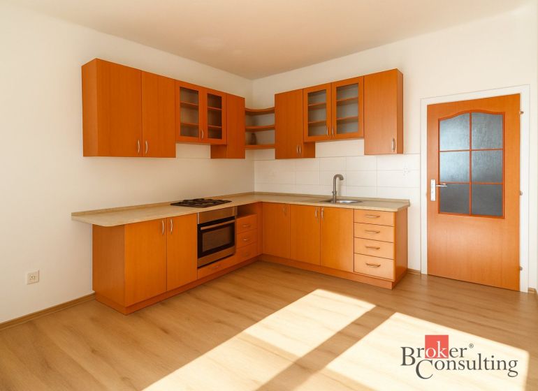 A kitchen in a 2-room apartment with wooden cabinets and a floor with a wood decor.