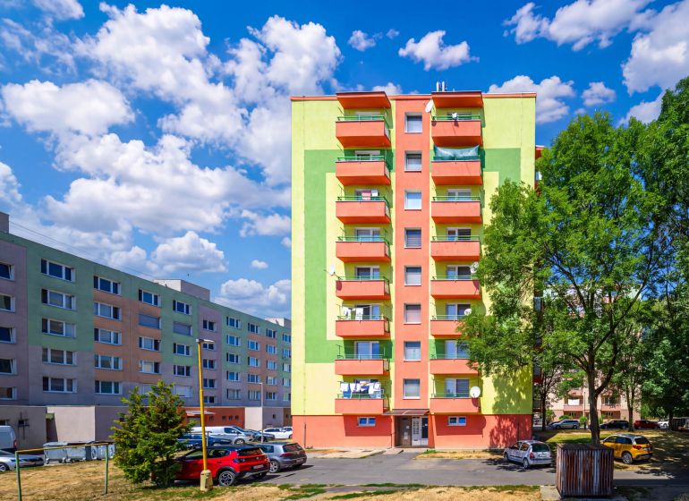 Colorful apartment buildings on Sládkovičova Street in Fiľakovo with parking and greenery.