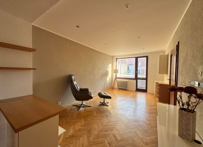 Living room in a four-room apartment with a wooden decor floor and a comfortable armchair.
