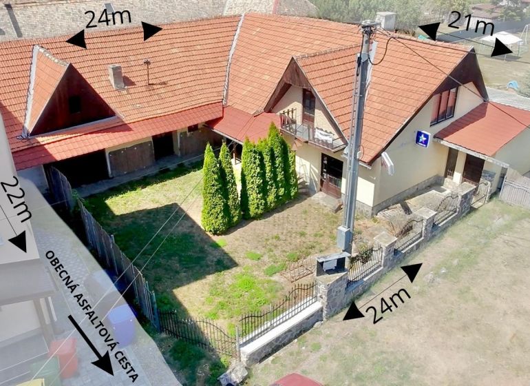A family house in the village of Dobrá Niva with a red roof and a yard surrounded by a fence.