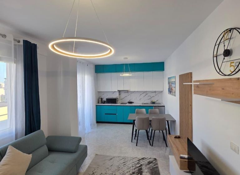 Living room of a two-room apartment with stylish lighting, kitchen, and comfortable sofa.