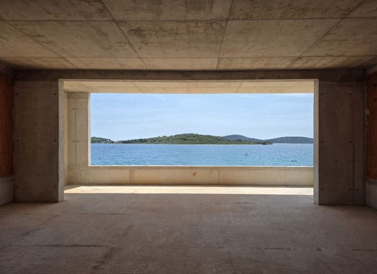 A view from a 4-room apartment of the sea and islands through a large window.