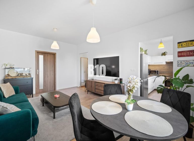 Living room in a two-room apartment with a wooden decor floor and a dining table.