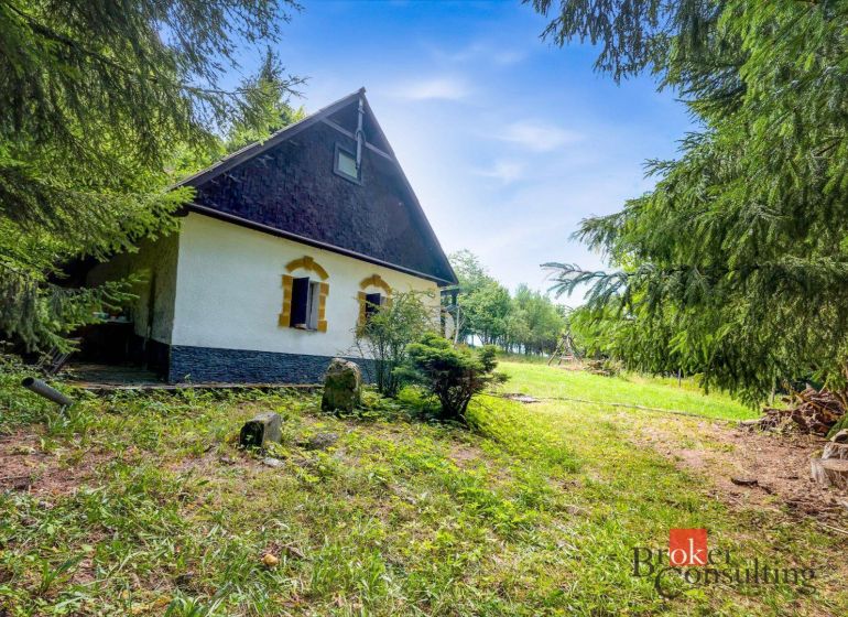 A cottage in Píla surrounded by greenery and coniferous trees, ideal for relaxation.