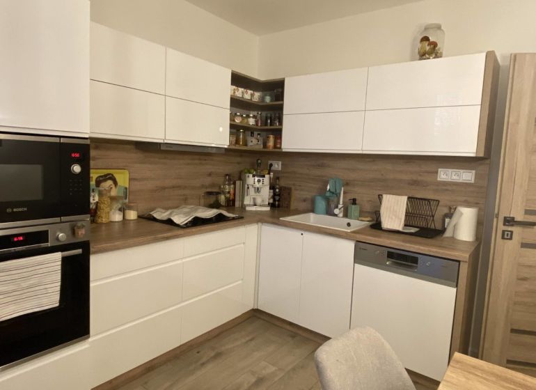 A kitchen in a 3-room apartment with white cabinets and a wood-patterned floor.