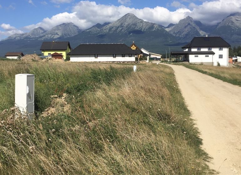 Residential plots in Mlynica with a view of the mountains and a dirt road.