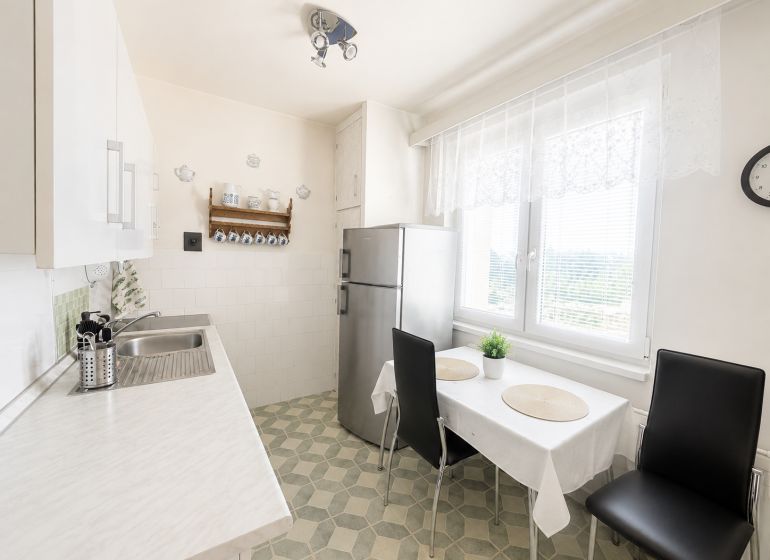 A kitchen in a 3-room apartment with white cabinets and a dining table.