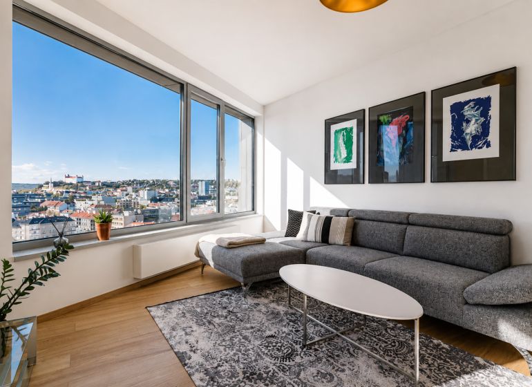 Living room in a three-room apartment with a wooden decor floor and a view of the city.