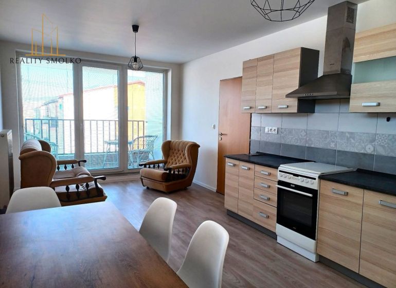 Living room with sofas, kitchen unit, and floor with wood decor in a two-room apartment.