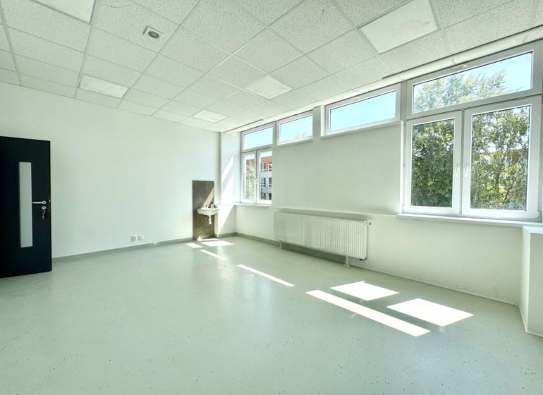 Bright commercial space with a sink and large windows, white walls.