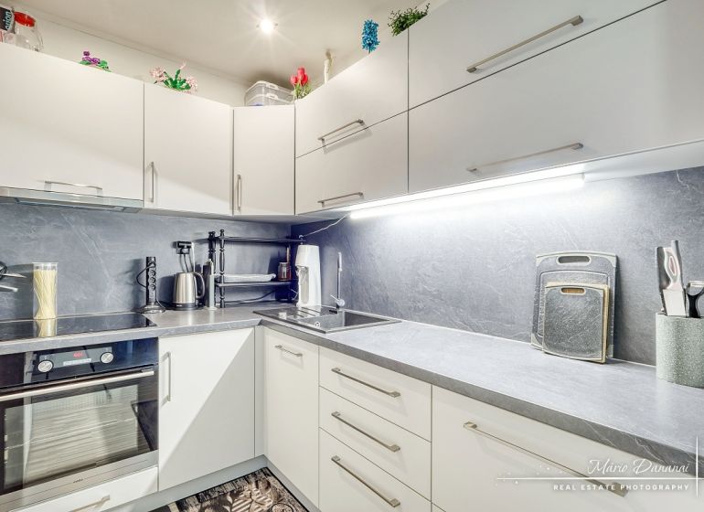 A kitchen in a studio apartment with white cabinets and appliances on the countertop.
