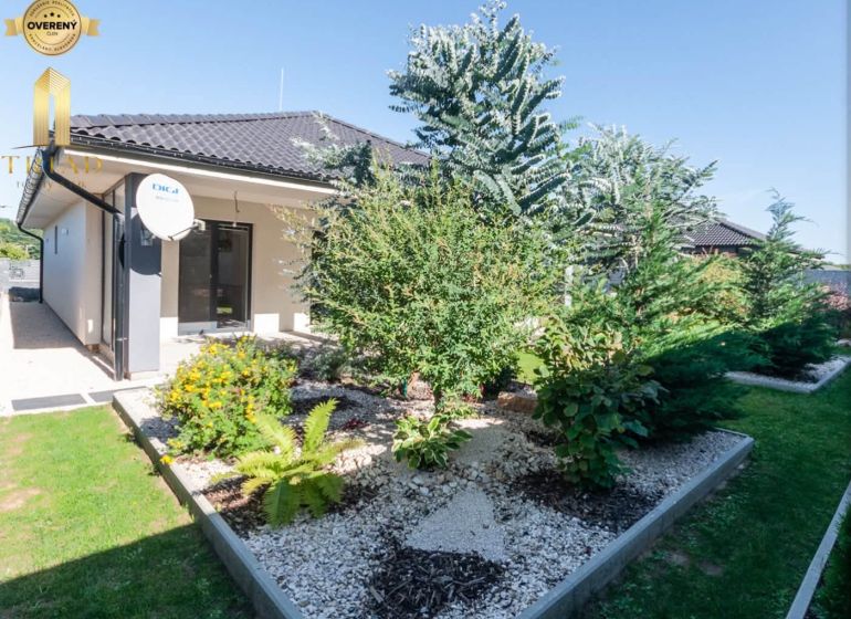 A family house in Bajč with a landscaped garden and a satellite dish.