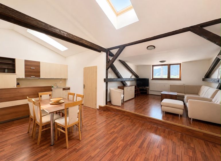 Living room with wood-patterned flooring and a kitchenette in a three-room apartment.