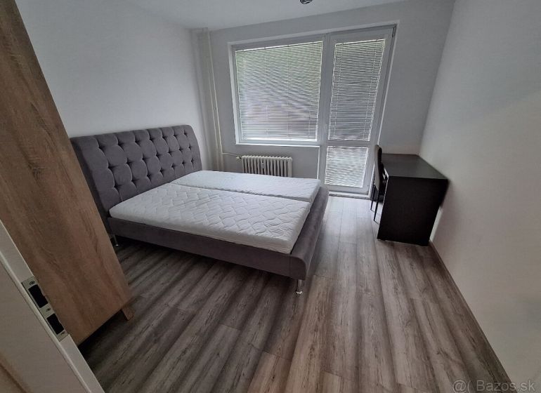 A bedroom in a 3-room apartment with a bed and a floor with a wooden decor.