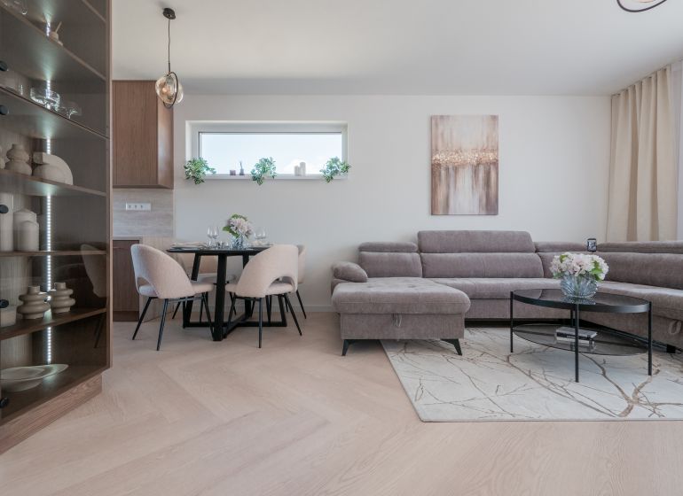 Interior of a family house with a wooden decor floor, a comfortable sofa, and a dining table.