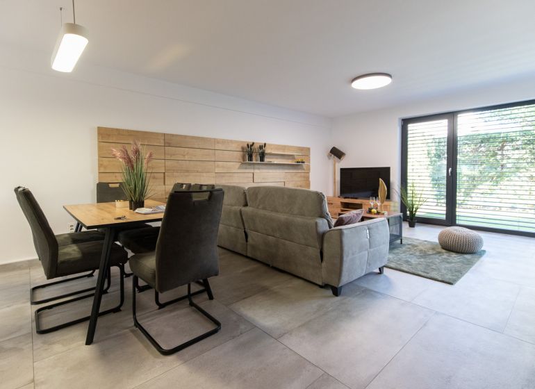 Living room in a 4-room apartment with large windows and comfortable seating furniture.