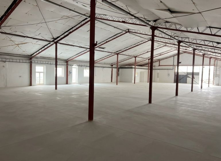 Spacious interior of a warehouse and hall with white walls and steel beams.