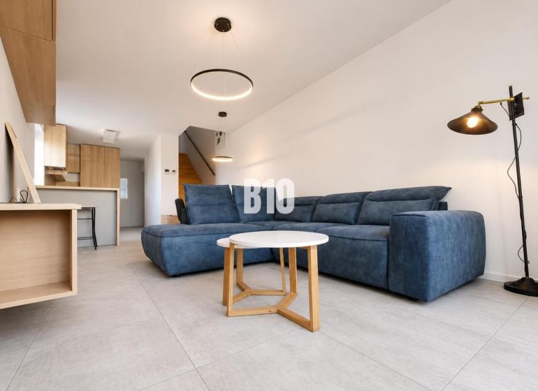 Recreational apartment with a blue sofa, a rectangular table, and plenty of light in the interior.