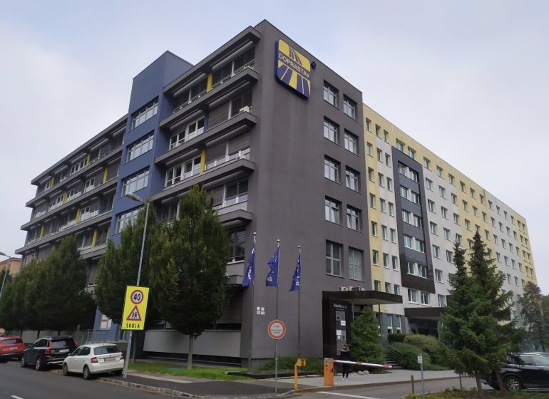 Offices in Bratislava - Ružinov on a busy street, next to greenery and parking.