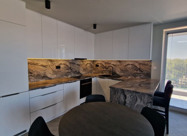 A kitchen with marble decor in a 3-room apartment and a window to the balcony.