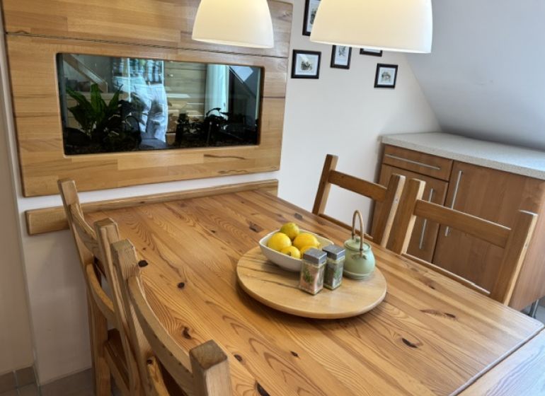 Dining area in a 4-room apartment with a table and a decorative aquarium on the wall.