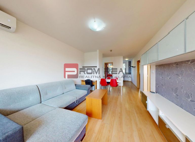 Living room in a 3-room apartment with a sofa, dining table, and wooden-patterned flooring.