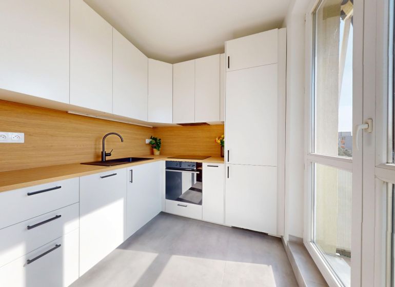 A kitchen in a 3-room apartment with white cabinets and a wood-patterned floor.