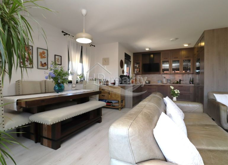 Recreational apartment with a kitchen, dining table, and sofa, floor with wooden decor.