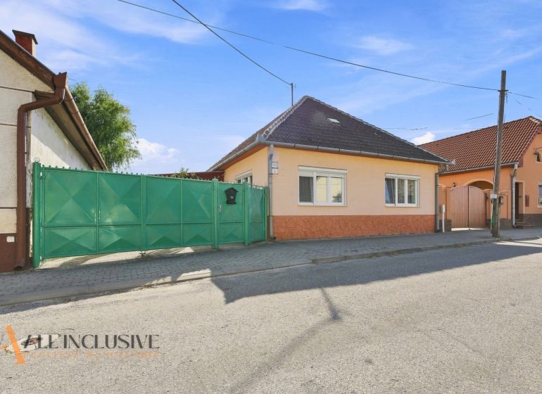 A family house in Veľký Meder with an orange facade and a green gate on the street.