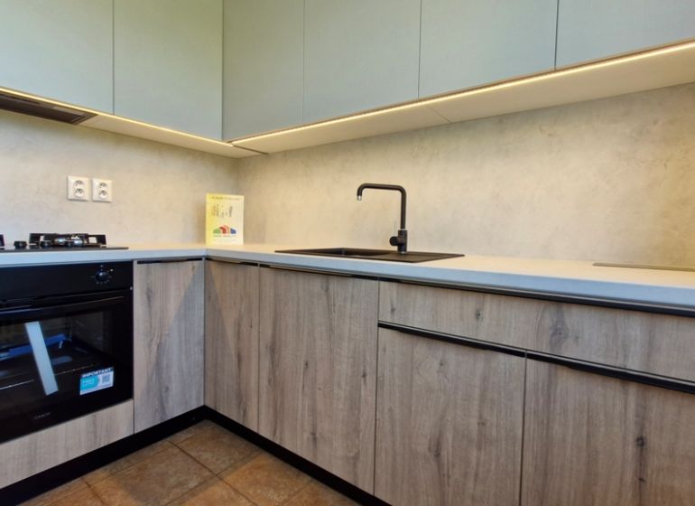 A kitchen in a 3-room apartment with a wooden decor floor and modern equipment.