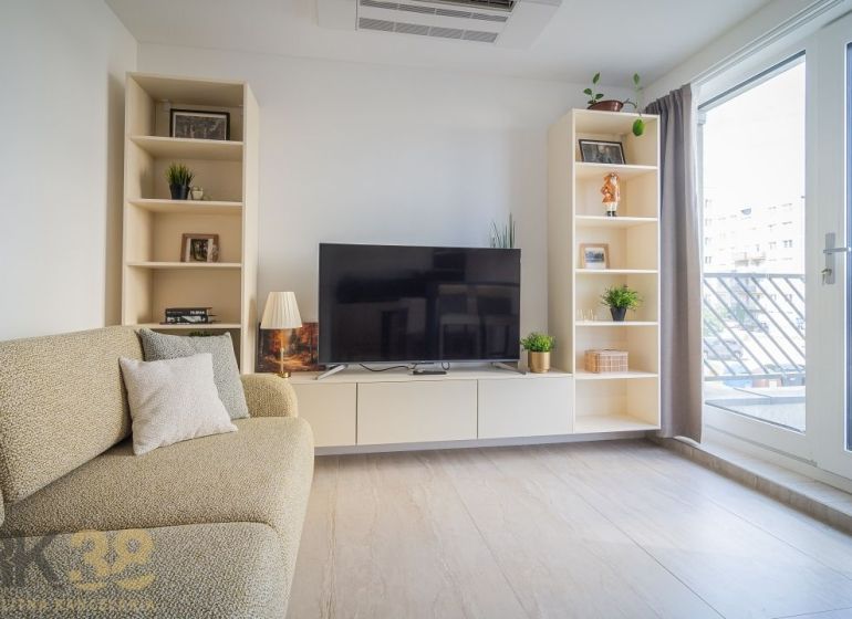 Living room with a television, sofa, and shelves in a 4-room apartment, floor with wooden decor.