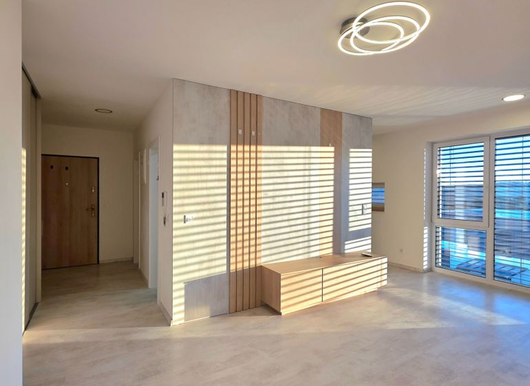 A bright living room with wood-patterned flooring and modern lighting in a two-room apartment.