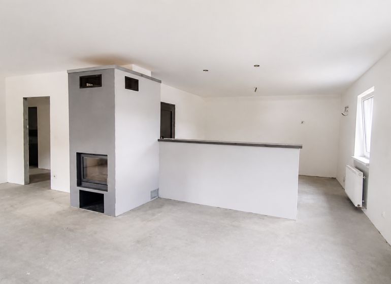 White room with a fireplace in a family house, floor with wooden decor.