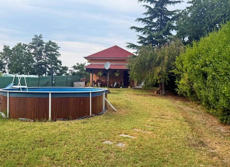 The exterior of the cottage in Komárno with a pool and a garden full of greenery.
