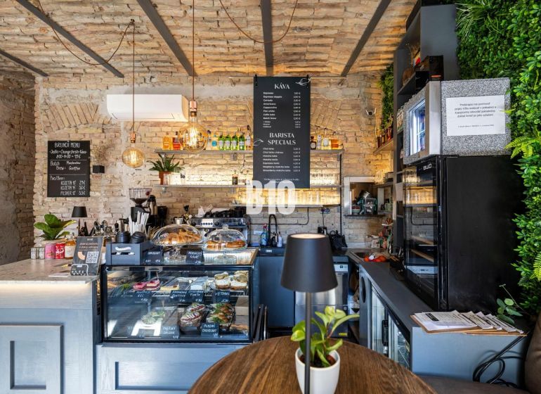 A café with brick walls, a counter with a menu of food and drinks, plants in the gastro area.