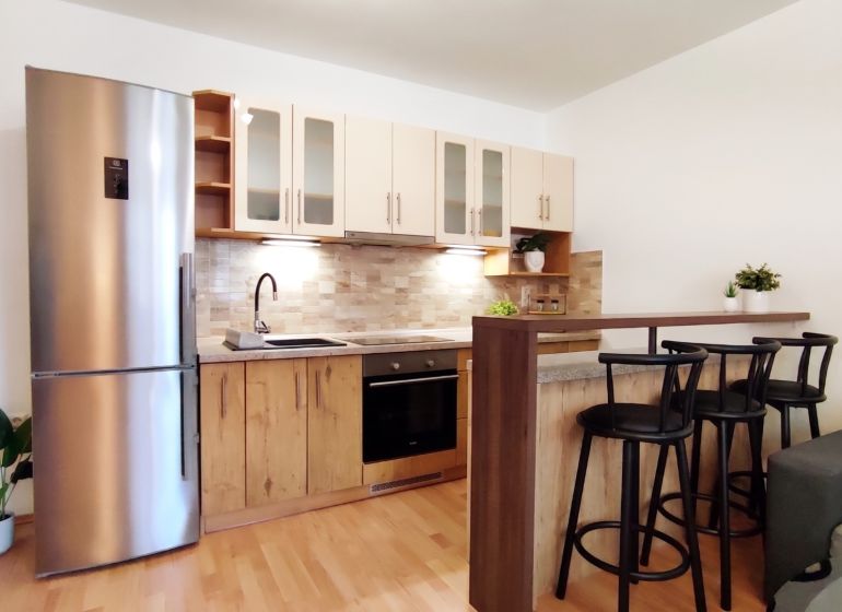 A kitchen in a 2-room apartment with a wooden decor floor and a bar counter.